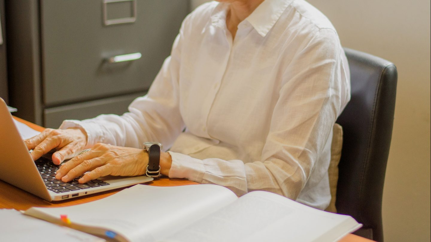 An office worker in her 60s uses a laptop